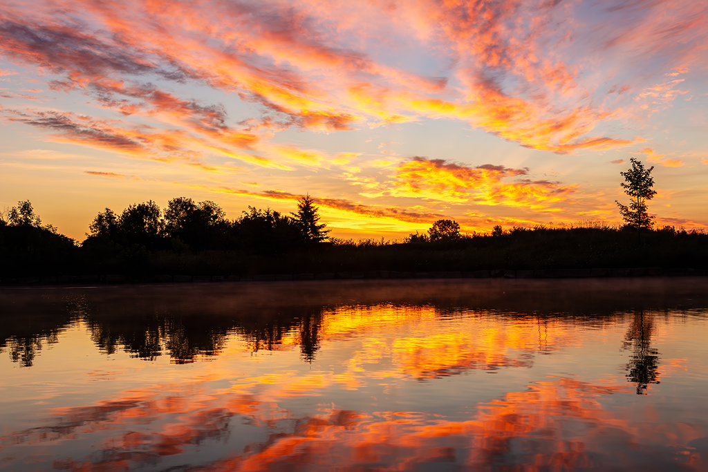 Golden reflections on peaceful waters—the serene beauty of a sunrise welcoming a new day. Kanata, Ontario