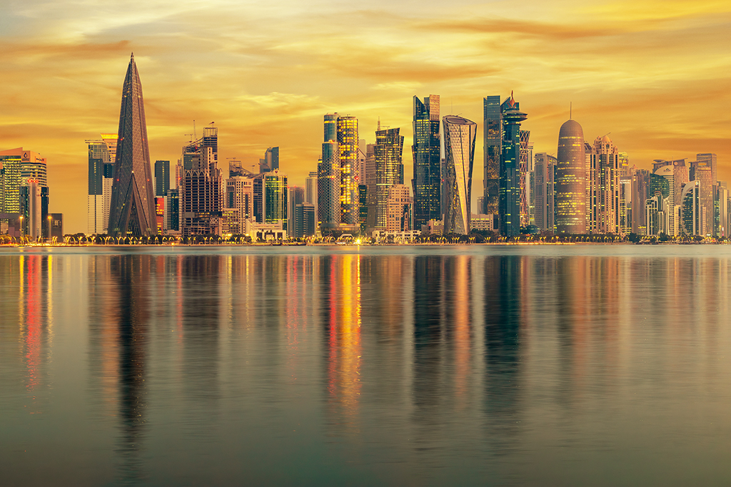 Awakening the city with golden hues, modern spires and intricate architecture stand tall and bold as dawn's light whispers through the air. Doha, Qatar.