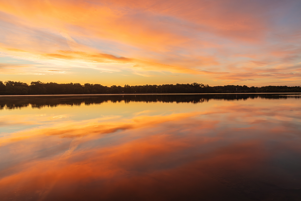 Soft golden hues stretch across the sky as the first light kisses the water, welcoming a brand-new day. Lac Leamy Lake, Gatineau, Quebec
